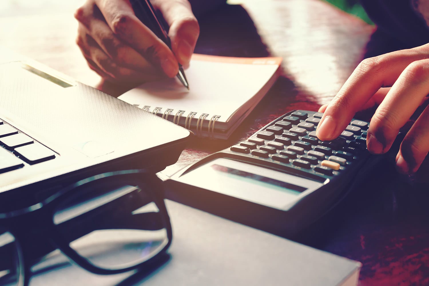 Close up woman hand using calculator and writing make note with
